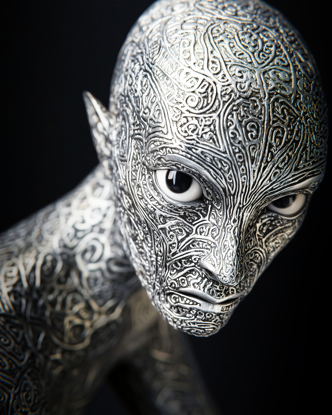 Metallic silver sculpture; intricate patterns; studio lighting